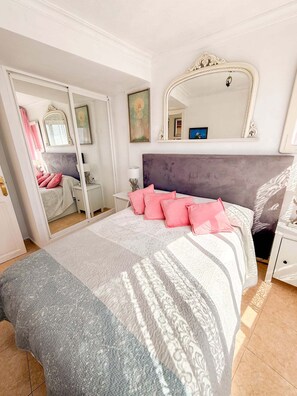 Ein Schlafzimmer mit einem Bett, einem Spiegel, einem Kleiderschrank und einem Nachttisch.