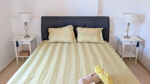 Un lit avec une literie à rayures, deux oreillers et une serviette pliée posée sur le lit.
