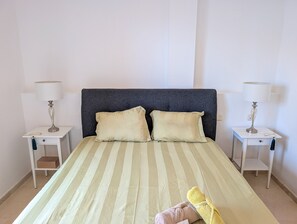 A bed with striped bedding, two pillows, and a folded towel on the bed. - Casa Lila: Sunny 2bed in Marbella (Marbella)