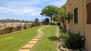 Un chemin menant à un bâtiment bordé de pierres, entouré de verdure et délimité par une clôture.