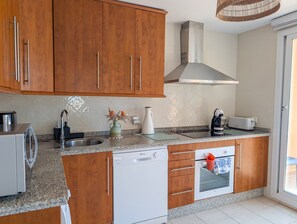 A kitchen with wooden cabinets, a dishwasher, a toaster, and a kettle. - Casa Lila: Sunny 2bed in Marbella (Marbella)