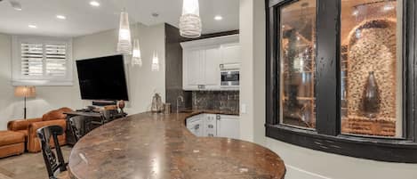 A modern kitchen with a curved island, pendant lighting, and a large window with a view.