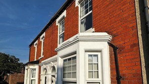 Een huis van rode baksteen met witte details en een erker.