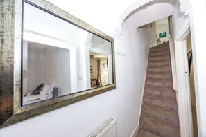 A hallway with a large mirror, a radiator, and a staircase. - Spacious 3BR House Near Sixfields, Duston (Northampton)