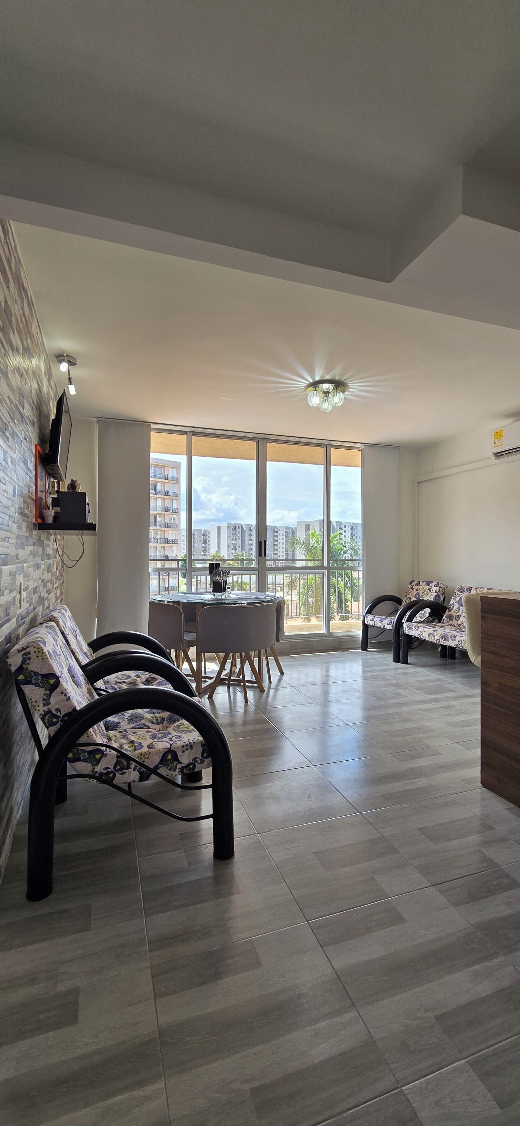Un vaste espace de vie comprenant une table à manger, des canapés et un balcon offrant une vue sur la ville.