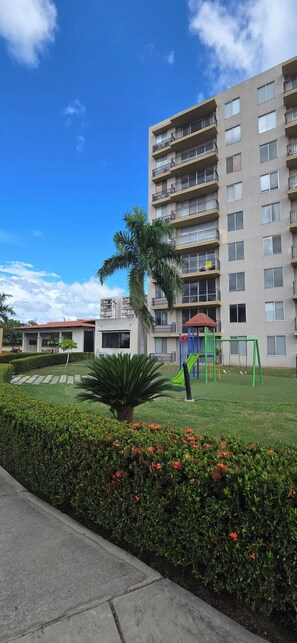 A residential building with multiple balconies, a playground, and a well-maintained garden. - Beautiful vacation apartment (Girardot)