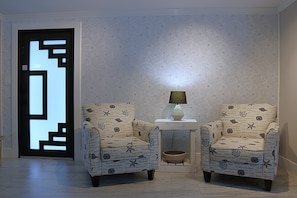 A room with two armchairs, a small table with a lamp, and a patterned wall. - Sarasota Silver Oasis - Private Pool, Near Beaches & Downtown (Sarasota)