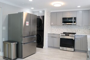 A modern kitchen with stainless steel appliances, grey cabinets, and a tiled backsplash. - Sarasota Silver Oasis - Private Pool, Near Beaches & Downtown (Sarasota)