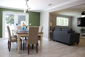 A dining area with a table and chairs, a sofa, and a television in a living room. - Sarasota Silver Oasis - Private Pool, Near Beaches & Downtown (Sarasota)