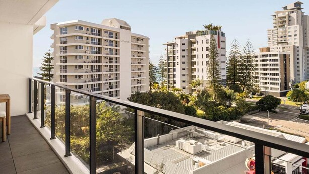Ein Balkon mit Blick auf hohe Gebäude, einen klaren Himmel und etwas Grün.