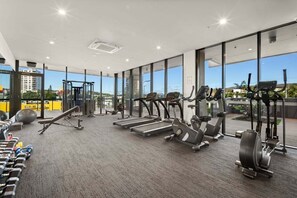 Ein Fitnessstudio mit Laufbändern, Crosstrainern und Kurzhanteln.