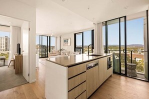 Eine moderne Küche mit einer großen Kochinsel, ein Essbereich mit einer Couch und ein Balkon mit Blick.