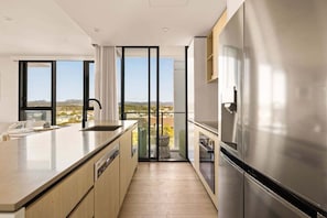 Cozinha moderna com uma ilha grande, eletrodomésticos de aço inoxidável e vista para a paisagem.