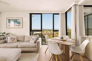 Ein modernes Wohnzimmer mit einer Couch, einem Esstisch mit Stühlen und einem großen Fenster mit Blick.