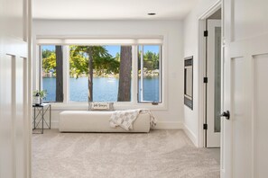 Habitació amb finestra gran que dona a un llac, una panxa i una porta.