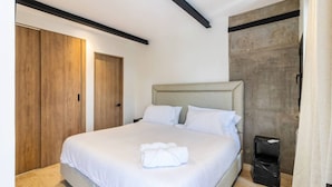 Een slaapkamer met een bed, een kledingkast en een afvalbak.