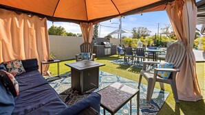 Un patio al aire libre con sofá, sillas, una mesa y una sombrilla.