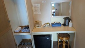 Habitación compacta con kitchenette, un refrigerador pequeño, un taburete y un espejo.