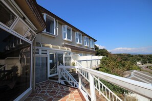 A residential building with a balcony, a staircase, and a view of the surrounding landscape. - Hotel Cliffside (Shimoda)