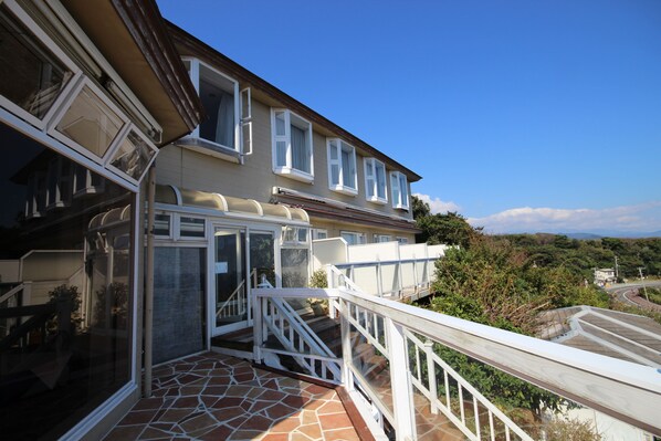 Un edificio residencial con balcón, escalera y vista del paisaje circundante.