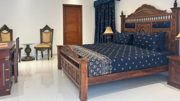Ein Schlafzimmer mit einem hölzernen Bett, einem Nachttisch, einem Sessel und einem Kleiderschrank.