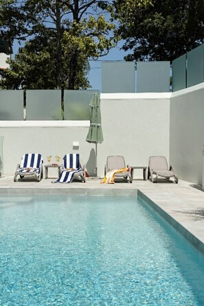 En pool med solstolar och ett bord.