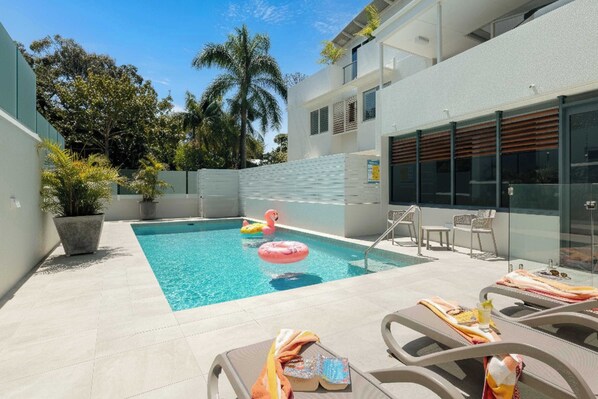 Ein Swimmingpool mit Liegestühlen und einem Flamingo-Schwimmpfiff.