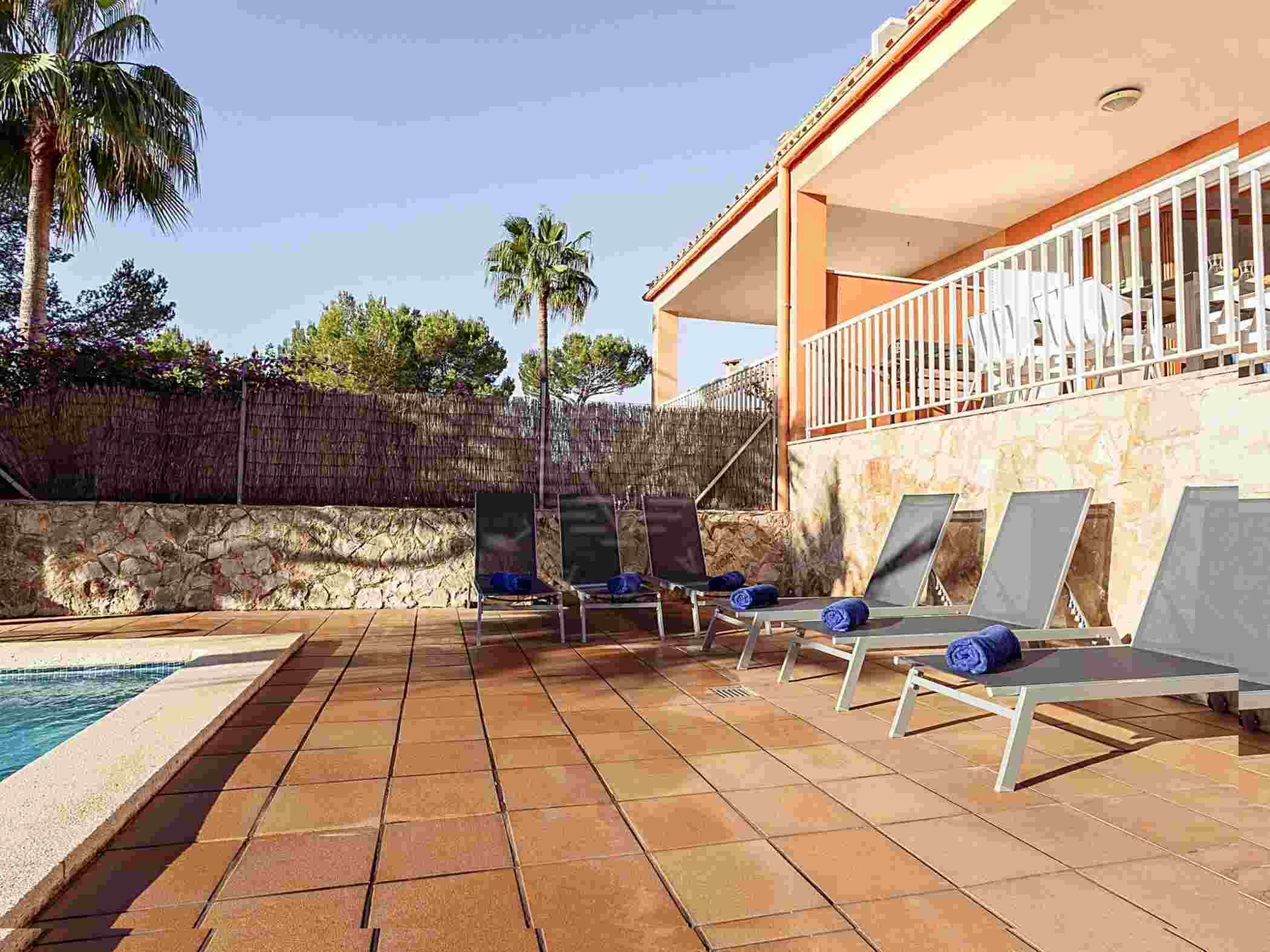 A poolside area with lounge chairs and a stone wall.