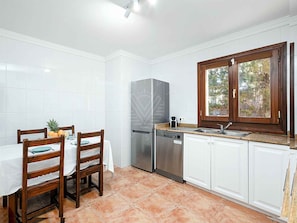 A kitchen with white cabinets, a stainless steel refrigerator, a dishwasher, and a window with a view of trees. - 'Chalet Mirador', with panoramic views of the Mediterranean Sea (Alcudia)