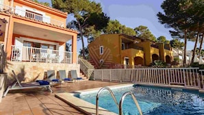 Ein Schwimmbecken mit Liegestühlen und ein Gebäude mit einem Balkon.