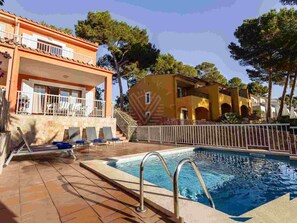 Ein Schwimmbecken mit Liegestühlen und ein Gebäude mit einem Balkon.