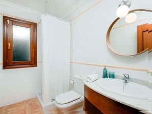 A bathroom with a toilet, a shower, a sink with a mirror, and a wooden cabinet. - 'Chalet Mirador', with panoramic views of the Mediterranean Sea (Alcudia)