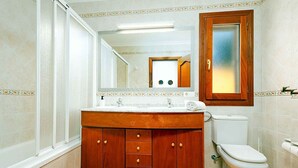Ein Badezimmer mit einem Holzbadezimmerhocker, einer Toilette und einem Spiegel.