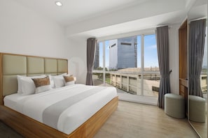 A modern hotel room with a large bed, a view of the cityscape, and a balcony. - Kavri by Kozystay - Kuningan (South Jakarta)