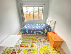 A child's bedroom with a bed, a small table, a wooden chest, and a play mat. - Surf, Beach, Fishing, Fishing, Relaxing, SUP, paddling, Restaurants, cafes (Currumbin)