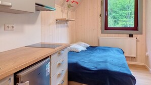 A bedroom with a bed, a small window, a radiator, a wooden desk, and a built-in dishwasher. - Hraničná by Interhome (Janov nad Nisou)