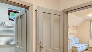 A room with a bed, a bedside table, a radiator, and a window with flowers. - Hraničná by Interhome (Janov nad Nisou)
