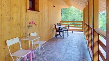 Ein Holzinterieur mit Tisch und Stühlen, einer Vase mit Blumen und Blick auf Grünfläche.