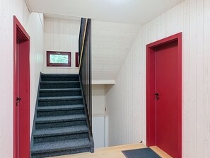 Een trap met een rode deur links en een rode deur rechts, die leidt naar een kamer met een raam.