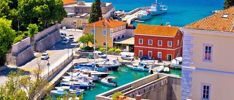 A coastal town with a marina, stone walls, and buildings with red-tiled roofs.