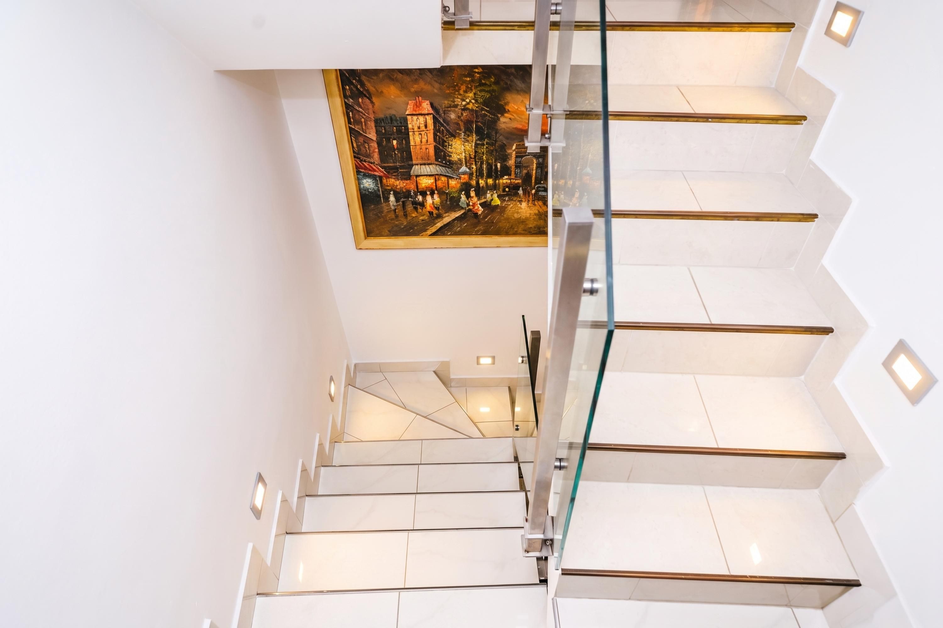 A modern staircase with glass railings and white tiles.