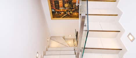 A modern staircase with glass railings and white tiles.