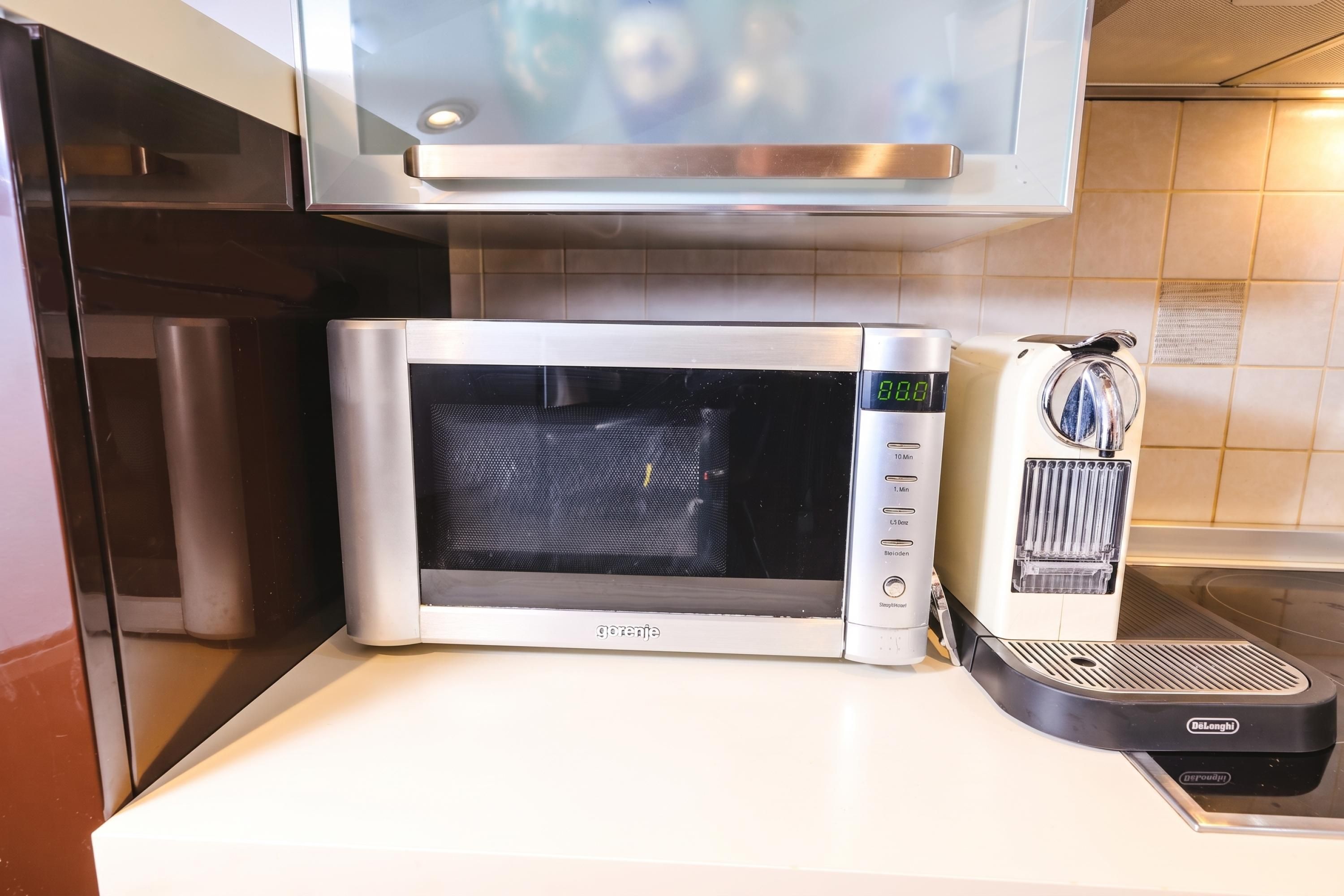 A kitchen with a microwave, a coffee machine, and a refrigerator.