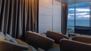 A modern hotel room with a large window, a flat-screen TV, and a seating area with sofas. - Sea View Large Luxury Space Beach Front (Pattaya)