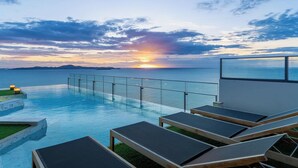 A poolside area with lounge chairs and a glass railing overlooking the sea during sunset. - Sea View Large Luxury Space Beach Front (Pattaya)