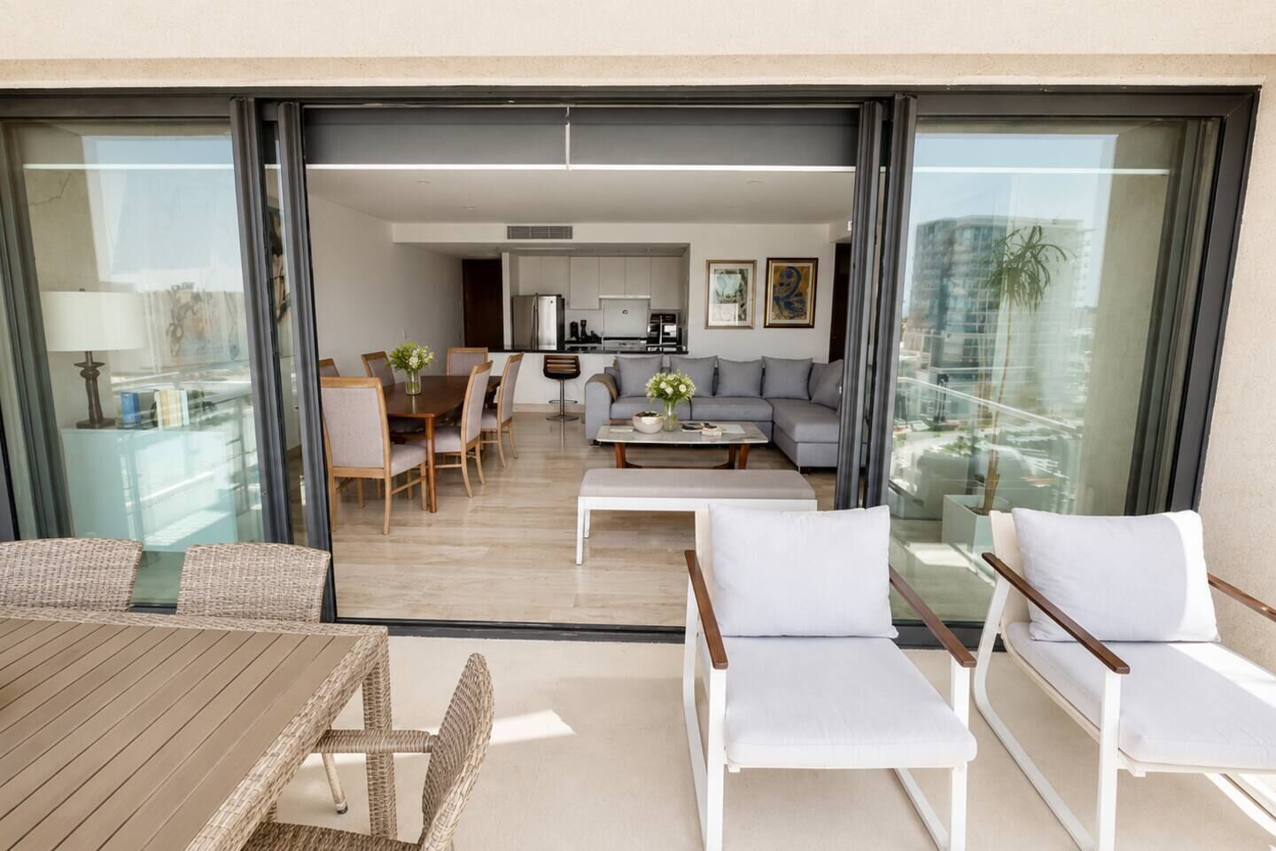 Un espace de vie moderne comprenant une table à manger, des chaises, un canapé et, au fond, une cuisine.