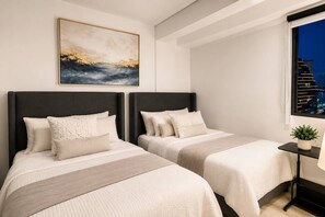 Ein Hotelzimmer mit zwei Betten, einem Nachttisch, einem Fenster mit Stadtblick und einem Bild an der Wand.