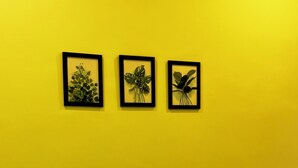 A room with a yellow wall and three framed botanical prints. - Tranquil 2-bedroom house with AC in delightful Varkala (Varkala)