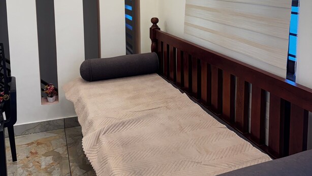 A bedroom with a bed, a window with blinds, a wall-mounted light fixture, and a small potted plant. - Tranquil 2-bedroom house with AC in delightful Varkala (Varkala)