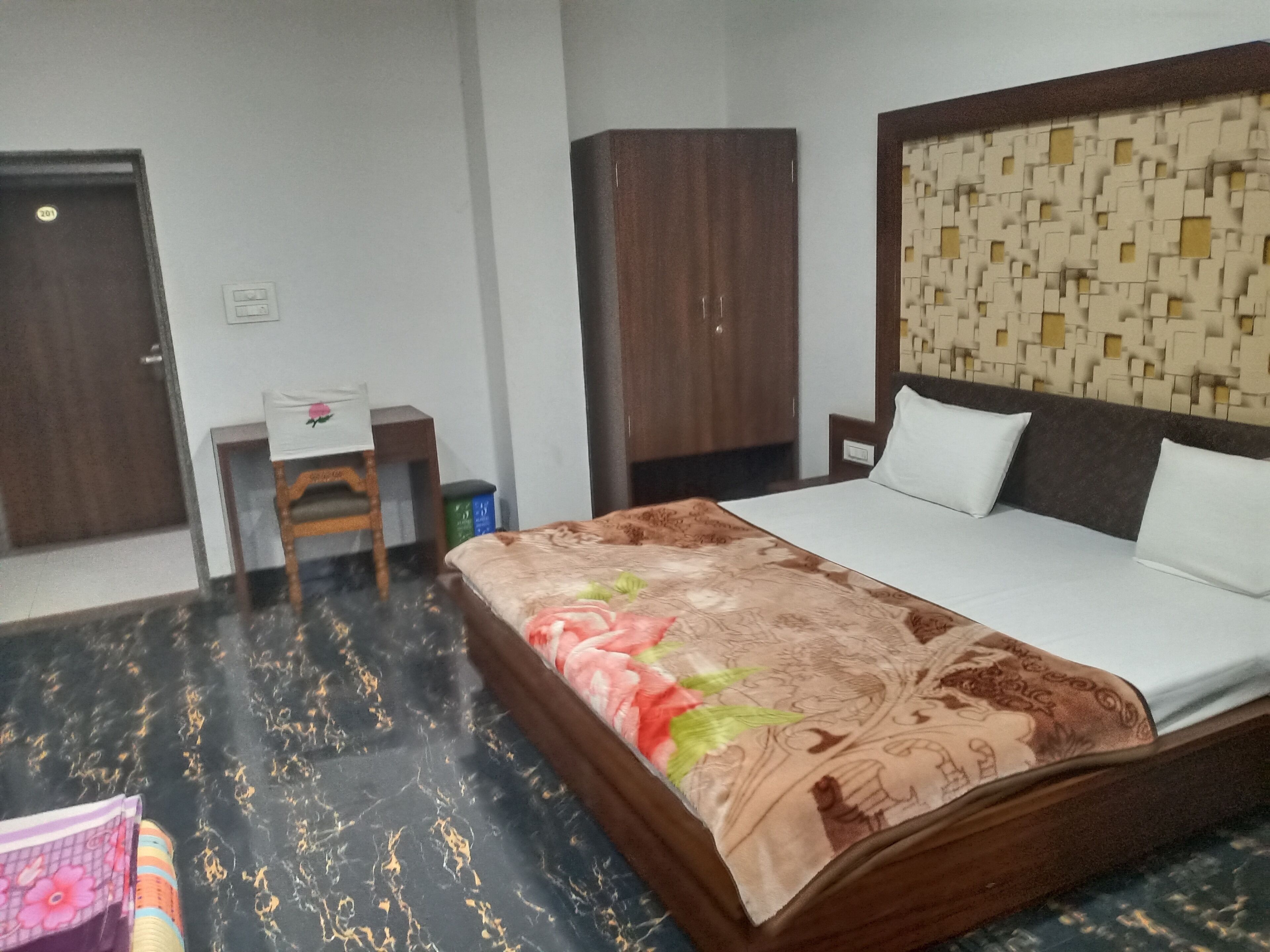 Ein Hotelzimmer mit einem Bett, einem Schreibtisch, einem Kleiderschrank und einem gemusterten Kopfteil.